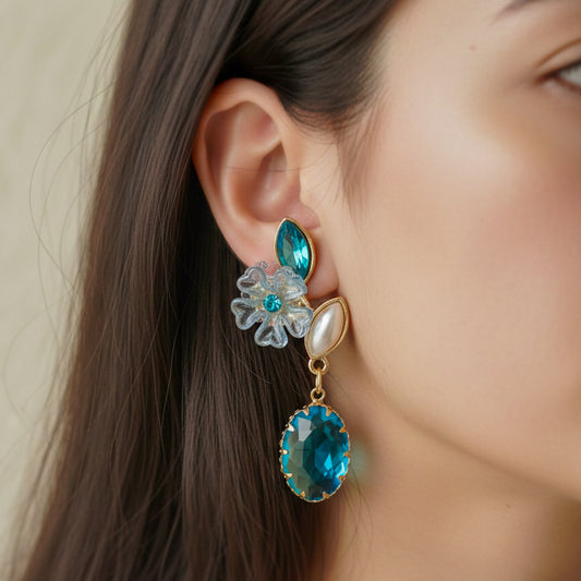 Teal oval drop earrings with floral studs and gold-tone charms, shown on ear