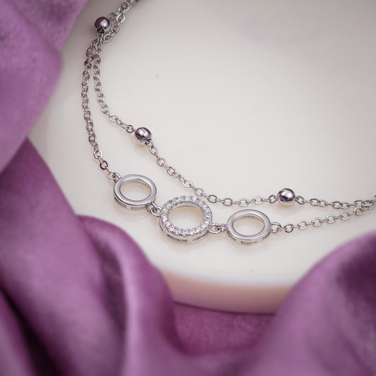 Close-up of stainless steel anklet with circular ring charms and small bead links
