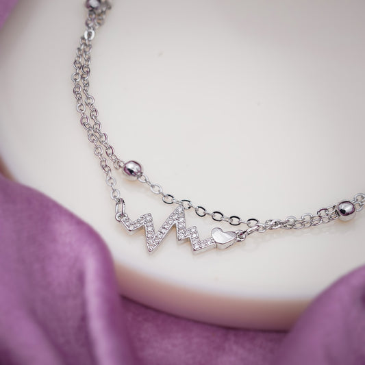 Stainless steel women’s anklet close-up with zigzag lightning pendant and bead links