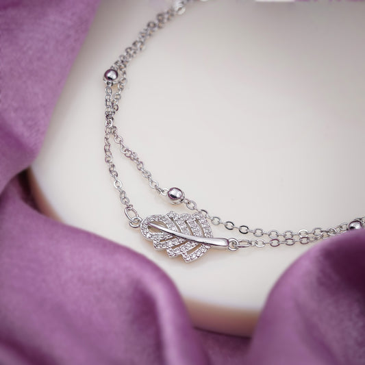 Silver-tone anklet close-up with leaf charm and oval bead details on chain