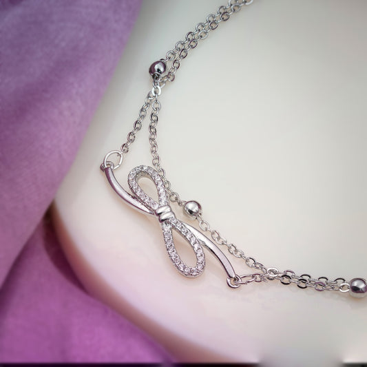 Silver-tone anklet bow charm with sparkling stones and heart-shaped side charms