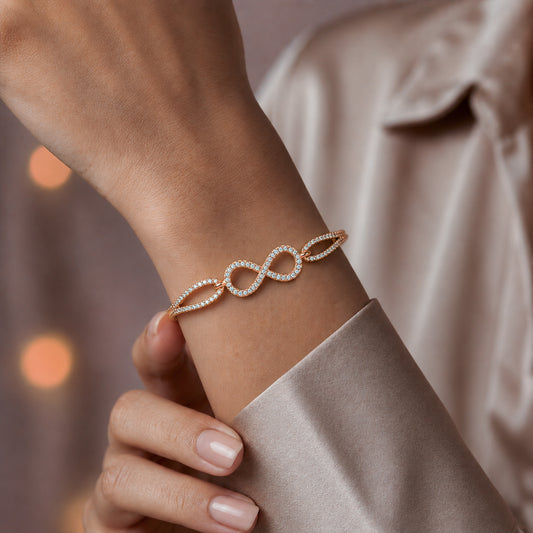 Gold CZ infinity knot bangle bracelet worn on wrist