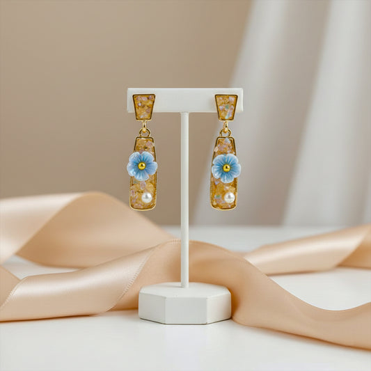 Gold-tone resin drop earrings with blue flower and pearl details, hanging geometric rectangles