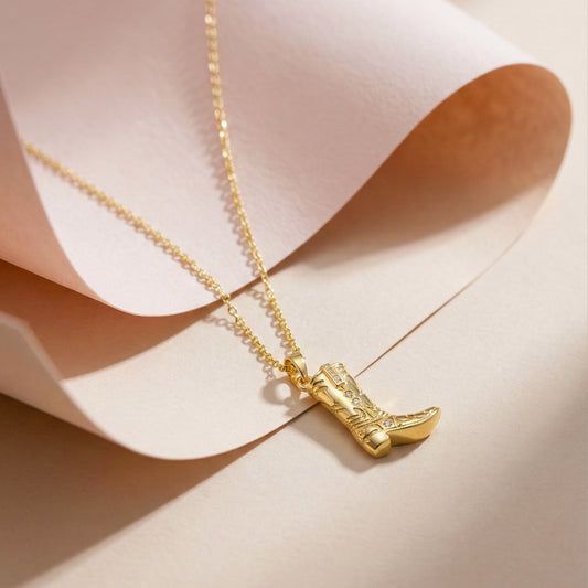 Gold-tone cowboy boot pendant on short chain, close-up view