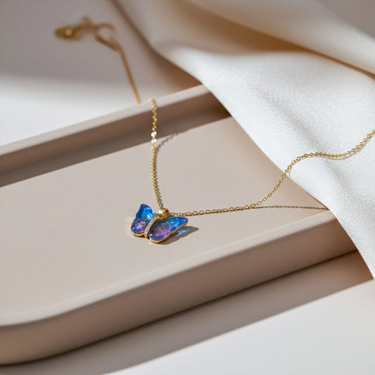 Iridescent blue resin butterfly pendant necklace on delicate gold chain