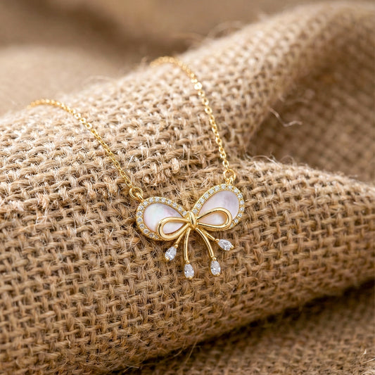 Gold bow pendant necklace with pink enamel center and small crystal tassels
