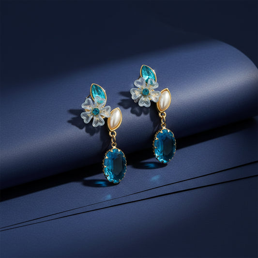 Teal oval drop earrings with floral studs and gold-tone charms, side view on display