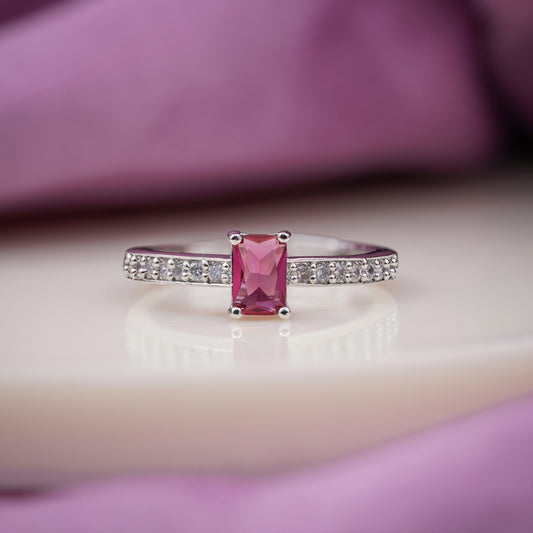 Silver ring with emerald-cut pink ruby-like center stone and pavé band