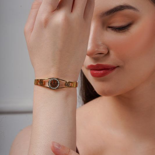 Gold-tone bangle with round heritage motif and ornate center detail