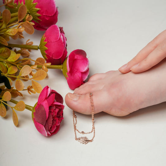 Rose gold dual-layer anklet with leaf charm chain, resting on the skin