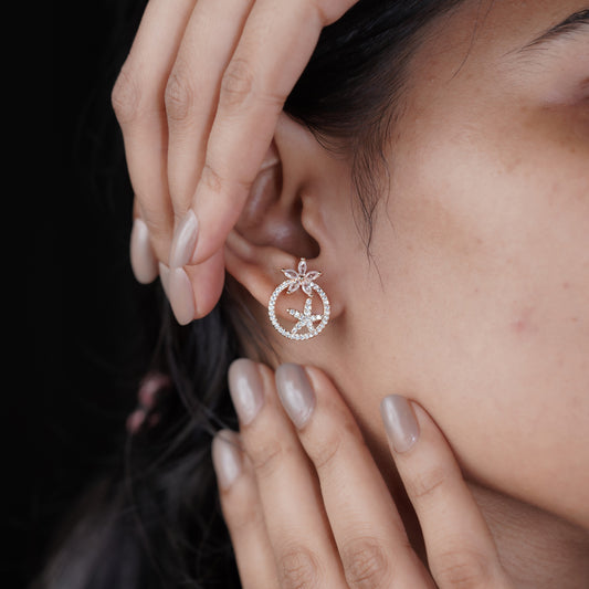 Rose gold CZ circle stud earrings with starflower topper, side view on ear.