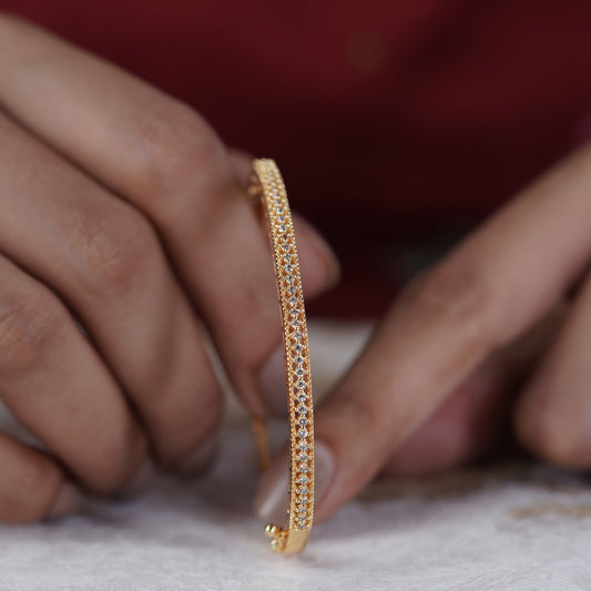 Gold triple-row CZ pavé kada bangle held upright by hands